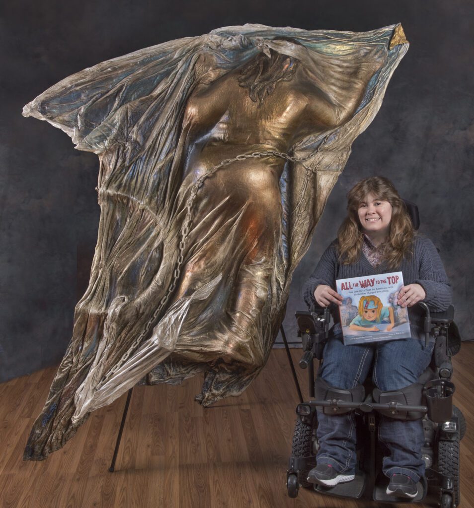 Jennifer Keelan-Chaffins sits in front of the sculpture created by Gina, which is twice her size.